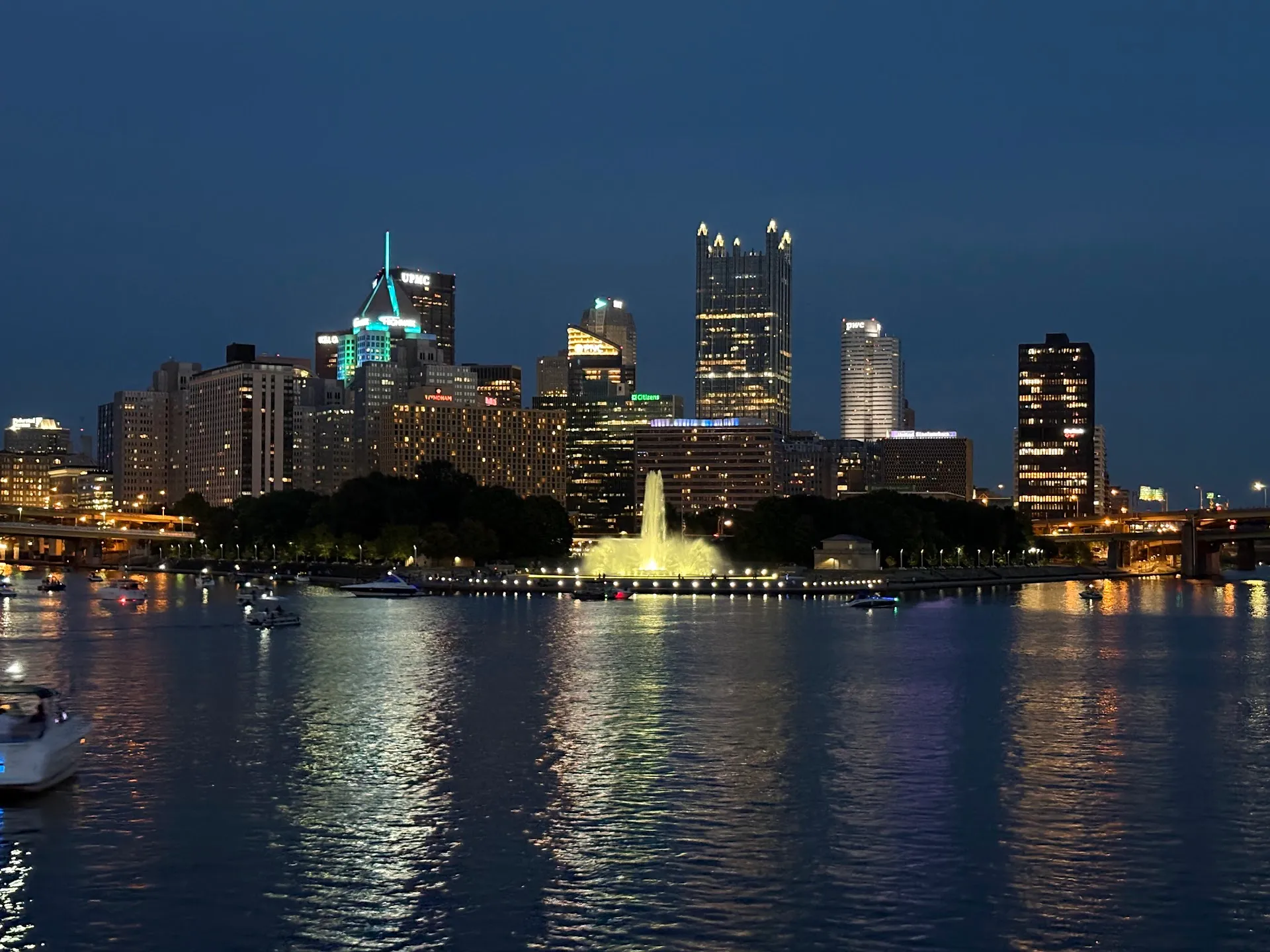 Pittsburgh skyline at dusk across the river, with the city lights reflected in the water